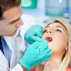 Врач осматривает зубы Острая форма лечится путем раскрытия нагноения